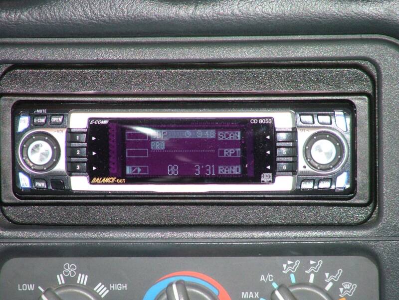Car stereo with digital display and controls.
