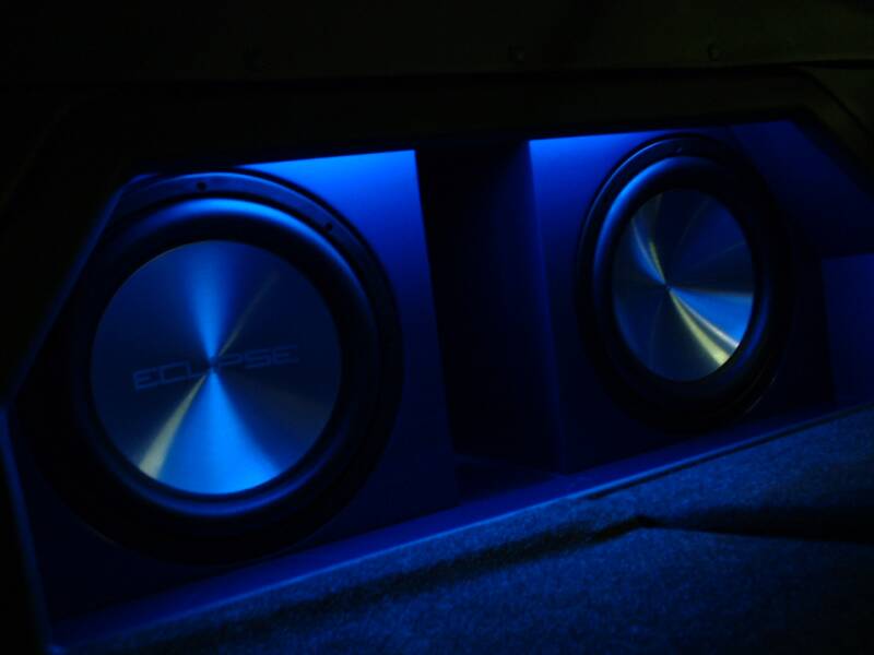 Blue-lit stereo speakers in a dark setting.