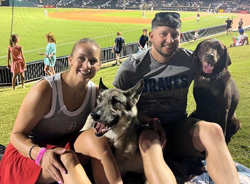 Couple at baseball game with two dogs